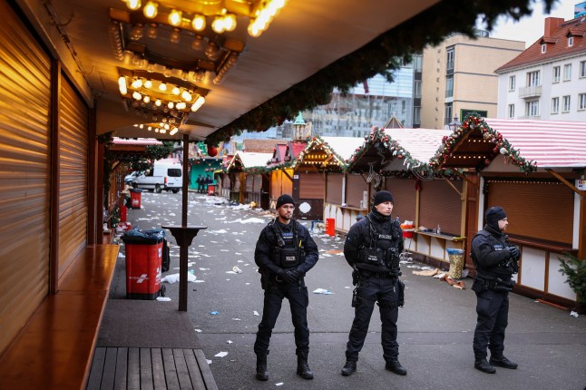 Puing-puing dan kios-kios yang ditutup terlihat ketika seorang petugas polisi berdiri di lokasi serangan penabrakan mobil di pasar Natal di Magdeburg, Jerman timur, 21 Desember 2024, menyebabkan beberapa orang tewas dan puluhan lainnya luka-luka. Media Jerman melaporkan bahwa jumlah korban tewas meningkat menjadi empat orang tewas dalam semalam dan 200 orang terluka dalam serangan tanggal 20 Desember itu. (Foto oleh Ronny HARTMANN / AFP) (Foto oleh RONNY HARTMANN/AFP via Getty Images)