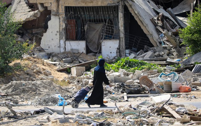 Seorang wanita Palestina berjalan di sepanjang sisa-sisa jalan melewati bangunan yang hancur, saat beberapa penduduk kembali ke kota Khan Yunis di selatan Jalur Gaza pada 30 Juni 2024, di tengah konflik yang sedang berlangsung antara Israel dan kelompok militan Palestina Hamas. (Foto oleh Eyad BABA / AFP) (Foto oleh EYAD BABA/AFP via Getty Images)