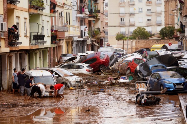 Warga memandangi mobil-mobil yang menumpuk usai tersapu banjir di Valencia, Spanyol, Rabu, 30 Oktober 2024. (AP Photo/Alberto Saiz)