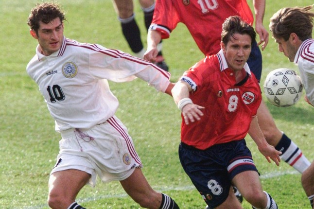 (FILES) Pemain Georgia Mikhail Kavelashvili (Kiri) berebut bola di stadion Ullevaal di Oslo 20 Mei 1999 saat kualifikasi grup 2 Euro 2000 Pada 27 November 2024, partai yang berkuasa di Georgia bernama Mikheil Kavelashvili, politisi sayap kanan, mantan. pesepakbola dan loyalis setia, sebagai calon presiden untuk 14 pemilu Desember, dengan tujuan untuk lebih mengkonsolidasikan kekuasaannya. (Foto oleh TOR RICHARDSEN / SCANPIX / AFP) (Foto oleh TOR RICHARDSEN/SCANPIX/AFP via Getty Images)