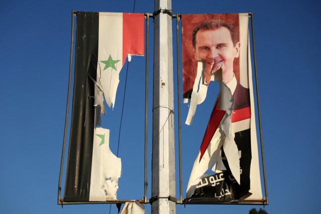 Sebuah papan iklan dengan foto Presiden Suriah Bashar al-Assad dan bendera nasional dirobohkan oleh pejuang anti-pemerintah di kota utara Aleppo 30 November 2024. Para jihadis dan sekutu mereka yang didukung Turki telah menyerbu kota Aleppo kedua di Suriah pada bulan November. Pada tanggal 29 Desember, mereka melancarkan serangan kilat terhadap pasukan pemerintah yang didukung oleh Iran dan Rusia. (Foto oleh Omar HAJ KADOUR / AFP) (Foto oleh OMAR HAJ KADOUR/AFP via Getty Images)