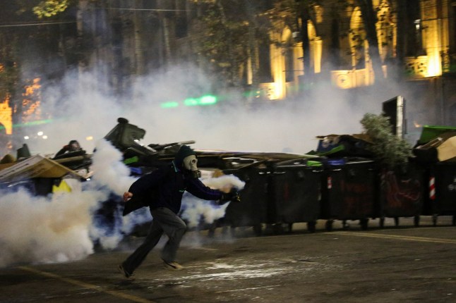 Seseorang yang memakai masker berlari dengan tabung gas air mata saat unjuk rasa memprotes keputusan pemerintah untuk menunda negosiasi keanggotaan Uni Eropa, di Tbilisi, Georgia 3 Desember 2024. REUTERS /Irakli Gedenidze