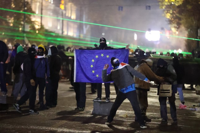 TBILISI, GEORGIA - 4 DESEMBER: Polisi menggunakan gas air mata saat pengunjuk rasa mengepung gedung Parlemen dan melemparkan kembang api serta benda-benda lainnya selama demonstrasi di ibu kota Georgia, Tbilisi, pada 4 Desember 2024. Para penggiat protes menentang keputusan untuk menunda negosiasi aksesi Georgia ke UE hingga 2028, di hari keenam. Ribuan demonstran, yang telah melakukan protes selama berhari-hari terhadap keputusan pemerintah Georgia yang menunda negosiasi keanggotaan negara tersebut di UE selama 4 tahun, mengakhiri protes mereka di pagi hari setelah polisi turun tangan. (Foto oleh Davit Kachkachishvili/Anadolu melalui Getty Images)