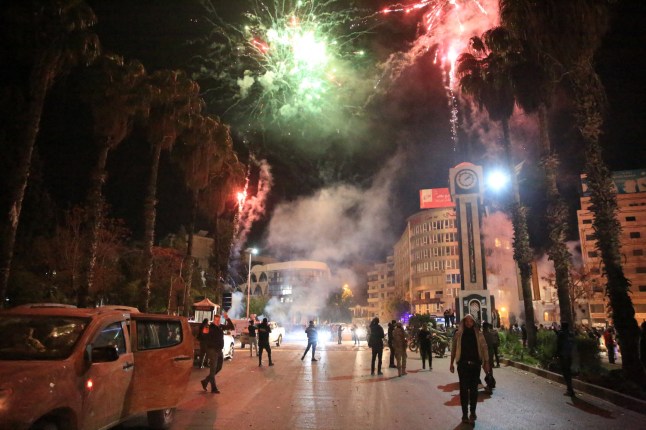 TOPSHOT - Les Syriens font la fête sur la place principale de Homs, le 8 décembre 2024, après l'entrée des forces rebelles dans la nuit dans la troisième ville de Syrie. Hayat Tahrir al-Sham (HTS) et les factions antigouvernementales alliées ont lancé une offensive éclair depuis le 27 novembre, balayant des pans entiers du pays du contrôle gouvernemental, notamment les grandes villes d'Alep, Hama, Homs et la capitale Damas. (Photo d'Aref TAMMAWI / AFP) (Photo d'AREF TAMMAWI/AFP via Getty Images) *** BESTPIX ***
