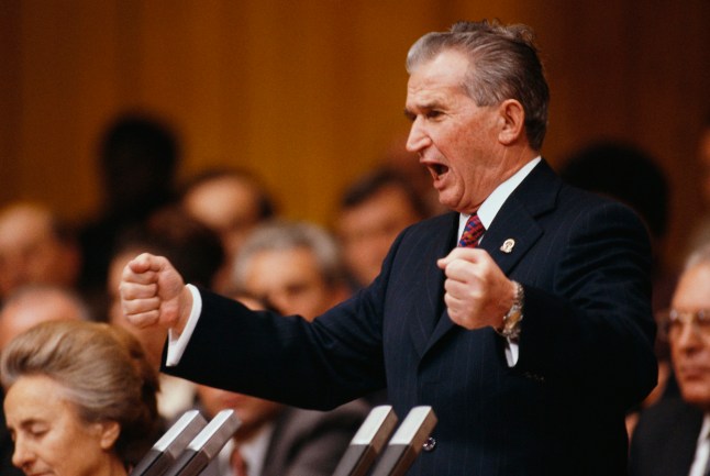 Presiden Rumania Nicolae Ceausescu berbicara dengan penuh semangat pada upacara penutupan kongres Partai Komunis Rumania ke-14 di Bukares, 24 November 1989. Istrinya Elena duduk di sebelahnya (kiri bawah). (Foto oleh Bernard Bisson/Sygma melalui Getty Images)