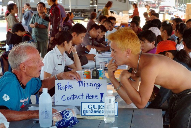 PATONG, THAILAND: Relawan Kanada Michael Furlong (kiri) membantu turis Thailand dan asing mencari kerabat yang hilang di depan rumah sakit pemerintah di Patong di pulau Phuket 28 Desember 2004, di mana korban tsunami yang terluka dan mayat yang ditemukan dibawa oleh tim penyelamat. Hampir 1.000 orang tewas, termasuk lebih dari 700 turis asing, di Thailand selatan, menurut wakil menteri dalam negeri. AFP PHOTO ROMEO GACAD (Kredit foto harus dibaca ROMEO GACAD/AFP melalui Getty Images)