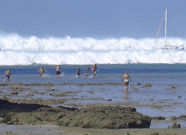 TOPSHOT - Wisatawan asing di atas pasir setelah air surut bereaksi ketika tsunami pertama dari enam tsunami mulai bergerak menuju pantai Hat Rai Lay dekat Krabi, Thailand selatan, 26 Desember 2004. Jumlah korban jiwa terakhir akibat bencana gelombang pasang di Thailand mungkin sudah dekat. 6800, saran Perdana Menteri Thaksin Shinawatra, ketika negara-negara Eropa bergabung dengan Thailand dalam upaya menemukan ribuan orang hilang. (Foto oleh AFP) (Foto oleh -/AFP via Getty Images)