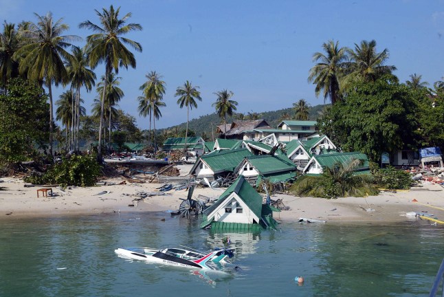 PHI PHI ISLAND, THAILAND: Sebuah perahu dan salah satu toko suvenir tenggelam di pantai Pulau Phi Phi di kota resor Thailand selatan, yang hancur akibat gelombang pasang pada tanggal 27 Desember 2004. Gempa bumi berkekuatan 9,0 di Skala Richter melanda pantai Sumatra, Indonesia, pada tanggal 26 Desember, dan tsunami serta gempa susulan yang terjadi kemudian merenggut nyawa lebih dari 17.800 orang di wilayah selatan dan tenggara Asia. AFP PHOTO/ROSLAN RAHMAN (Kredit foto harus dibaca ROSLAN RAHMAN/AFP via Getty Images)