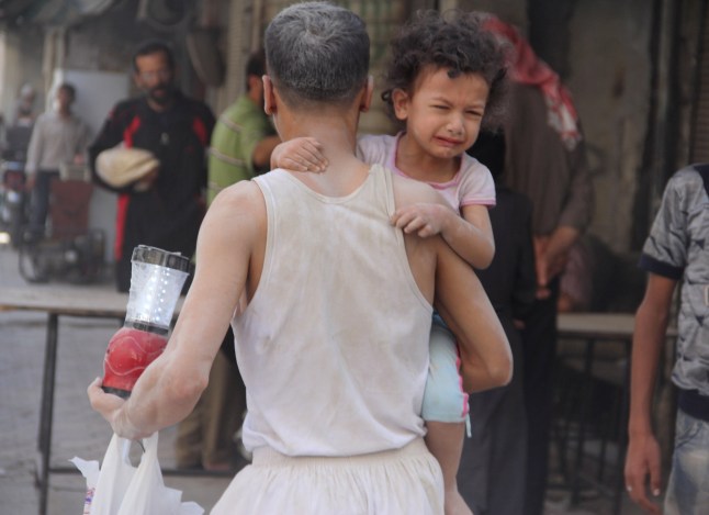 ALEPPO, SURIAH - 22 AGUSTUS: Seorang pria membawa seorang anak yang menangis dan beberapa barang miliknya membawa mereka ke daerah aman setelah serangan bom barel pasukan Assad di lingkungan Qadi Askar, meninggalkan korban pada 22 Agustus 2015, di Aleppo, Suriah. (Foto oleh Ahmed Muhammed Ali/Anadolu Agency/Getty Images)