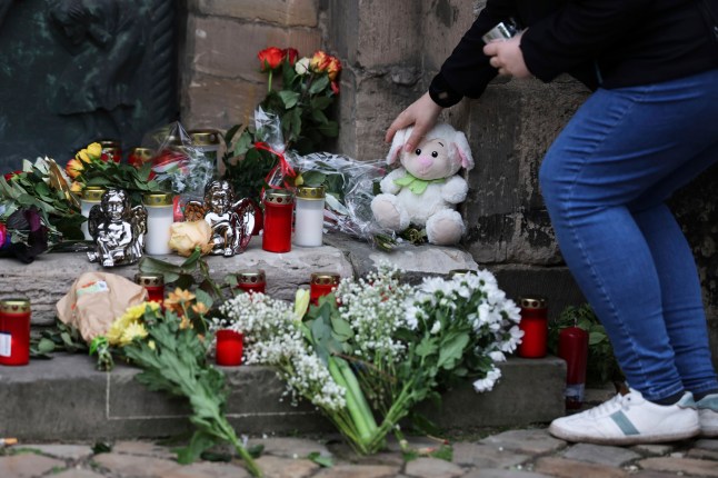 Seorang wanita meletakkan mainan lunak di situs peringatan Gereja St. John di Magdeburg, Jerman, Sabtu, 21 Desember 2024, pagi hari setelah seorang pengemudi menabrak sekelompok orang di pasar Natal Magdeburg. (Woitas Januari/dpa melalui AP)