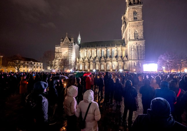 Orang-orang menghadiri upacara peringatan di depan katedral dekat pasar Natal di mana sebuah mobil melaju ke kerumunan Jumat malam, di Magdeburg, Jerman, Sabtu, 21 Desember 2024. (AP Photo/Michael Probst)