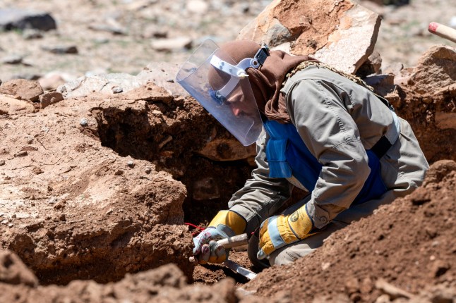 Dalam foto yang diambil pada 13 Mei 2024 ini, seorang penjinak ranjau Afghanistan dari Halo Trust membersihkan ranjau anti-tank dari desa Qala Khail, provinsi Ghazni. Jamur hitam baru saja hilang di provinsi Ghazni ketika anak-anak berkumpul di tepi kawah yang diciptakan oleh tambang, salah satu alat yang membunuh seorang anak setiap dua hari di Afghanistan. (Foto oleh Wakil KOHSAR / AFP) / Untuk menyertai laporan AFP tentang anak-anak yang kecelakaan ranjau di Afghanistan, LAPORAN oleh Qubad Wali dan Pascale Trouillaud (Foto oleh WAKIL KOHSAR/AFP via Getty Images)