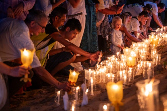 Para pelayat meletakkan lilin di pantai untuk upacara peringatan di Taman Peringatan Tsunami Ban Nam Khem pada 26 Desember 2024 di Phang Nga, Thailand.