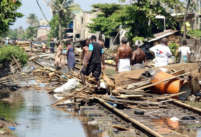 Warga berjalan cepat melewati bekas kehancuran di sepanjang jalur kereta api pesisir di kota Lunawa, Sri Lanka selatan, 26 Desember 2004, setelah gelombang pasang tsunami melanda lebih dari separuh garis pantai Sri Lanka.